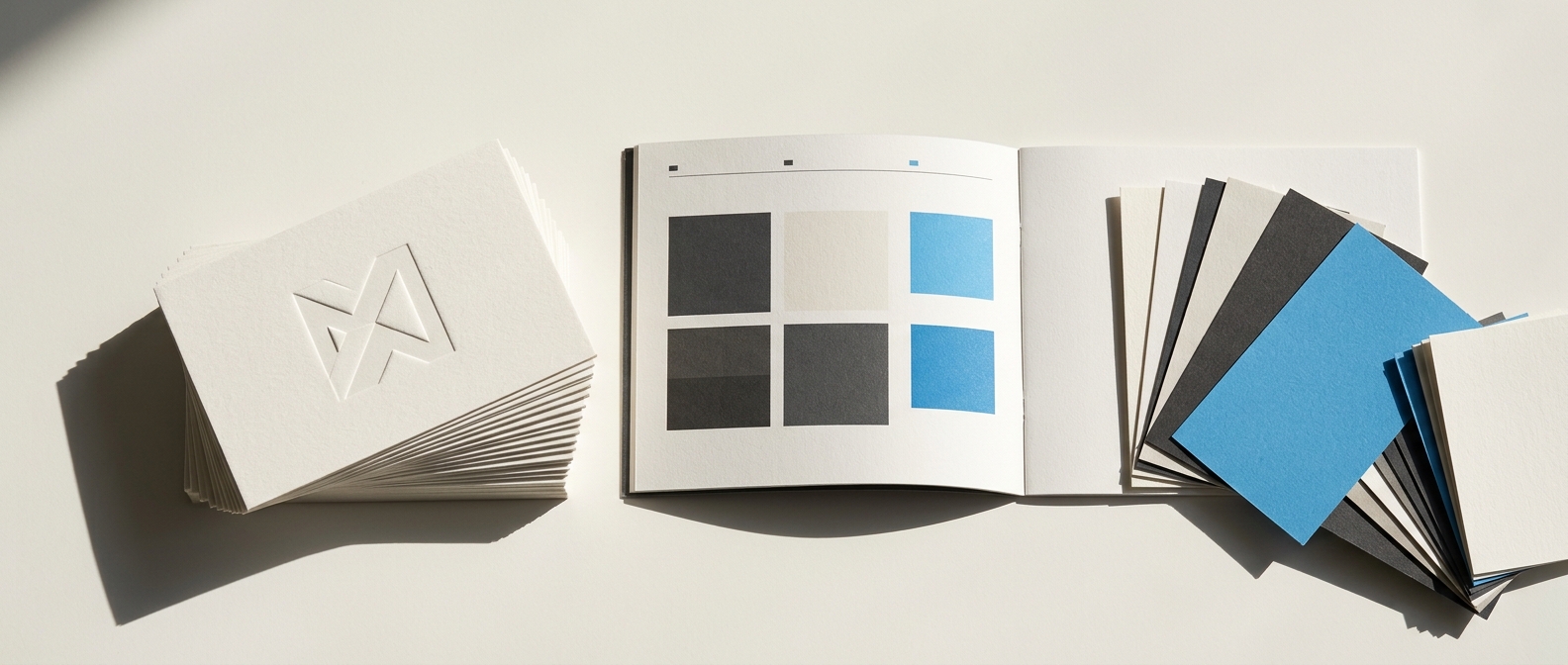 Embossed business cards, a brand guide and paper colour swatches in daylight